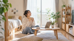 自然光の入る部屋でくつろぐ女性の一人暮らしのイメージ（AI生成画像）
