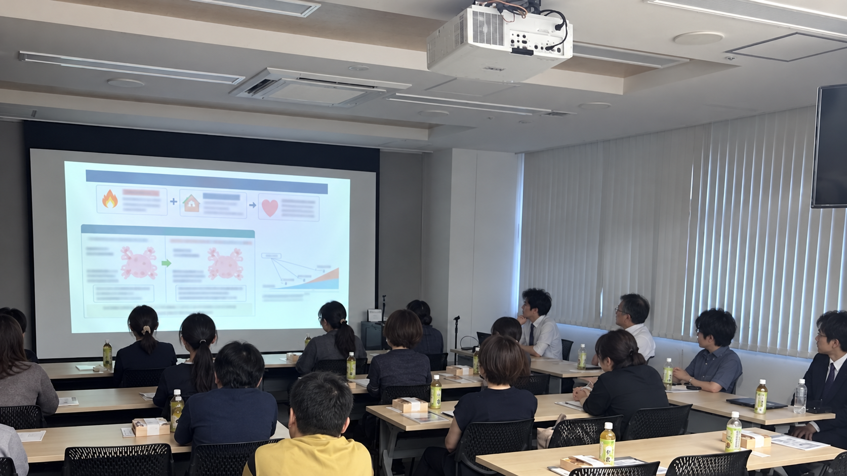 スクリーンを見ながら学ぶ研修風景(人物の顔をAIで加工)